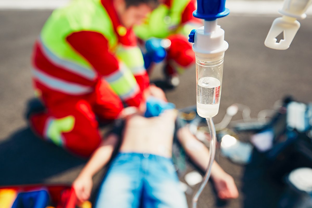 Emergency responders treating a motorcycle accident victim on the ground